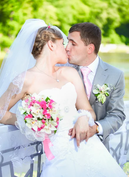 Portrait of young bride and groom kissing on sunny day outdoors — Stock Photo, Image