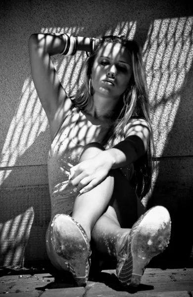 Black and white portrait of sexy woman sitting on ground and leaning against wall — Stock Photo, Image