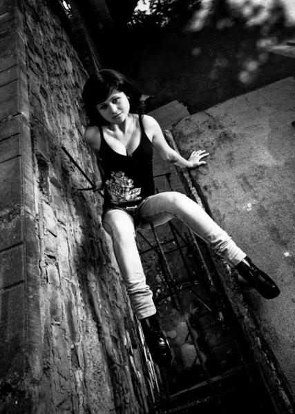 Portrait of sexy woman sitting on ground against brick wall — Stock Photo, Image