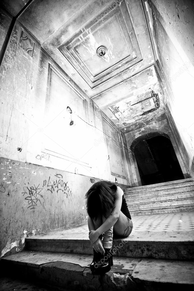 Depressed lonely woman sitting on stairs at abandoned building