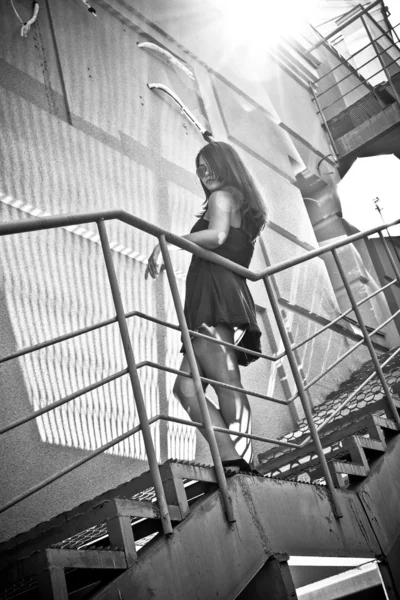 屋外の金属の階段の上に立って、セクシーなブルネットの女性の写真 — ストック写真
