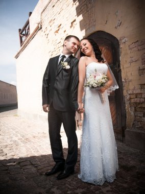 Gelin ve damat birbirine bakarak eski kalede portresi