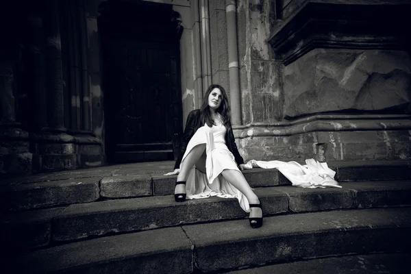 Photo of woman in long dress sitting on stone stairs at castle — Stock Photo, Image