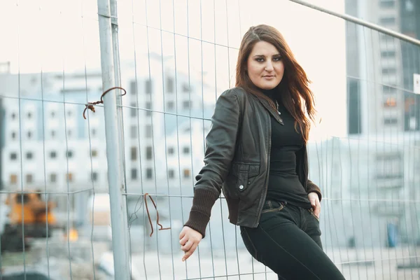 Toned portrait of sexy woman leaning against metal fence — Stock Photo, Image