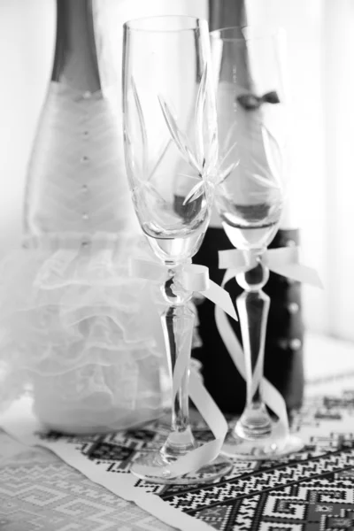Black and white shot of wedding glasses and decorated bottles — Stock Photo, Image