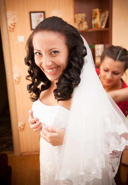 Портрет подружки невесты, завязывающей корсет на платье невесты — стоковое фото