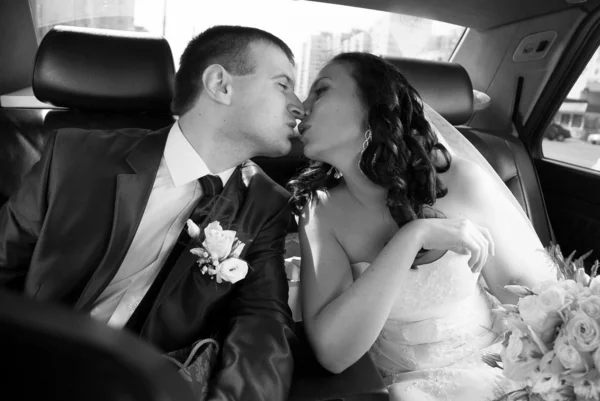 Retrato de novia y novio besándose en el asiento trasero del coche — Foto de Stock