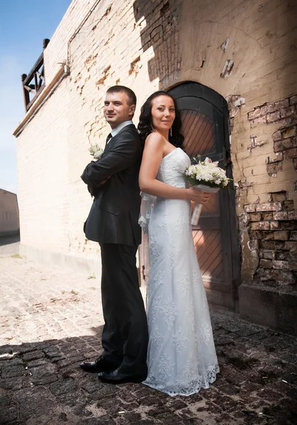 Novia y novio de pie espalda con espalda y mirando a la cámara en el castillo — Foto de Stock