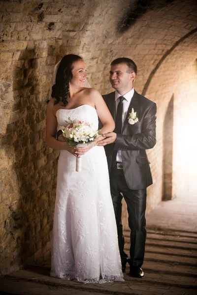 Retrato de noivo bonito abraçando noiva no túnel antigo — Fotografia de Stock