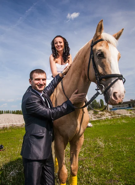 Groom holding horse with bride in saddle by rein — Stock Photo, Image