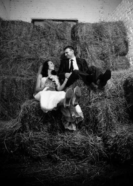 Shot of bride and groom sitting on stack of hay — Stock Photo, Image