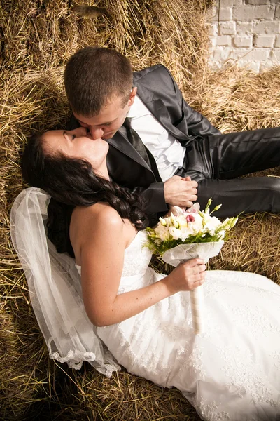 Portrait of beautiful bride and groom kissing on stack of hay — Stock Photo, Image