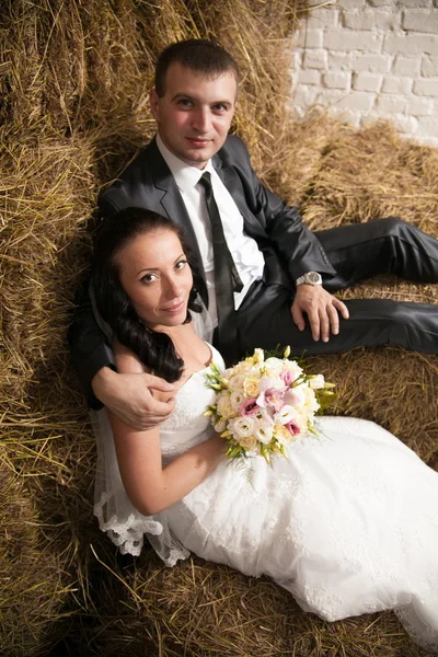 Porträt von Braut und Bräutigam, die sich im Stall auf Heu umarmen — Stockfoto