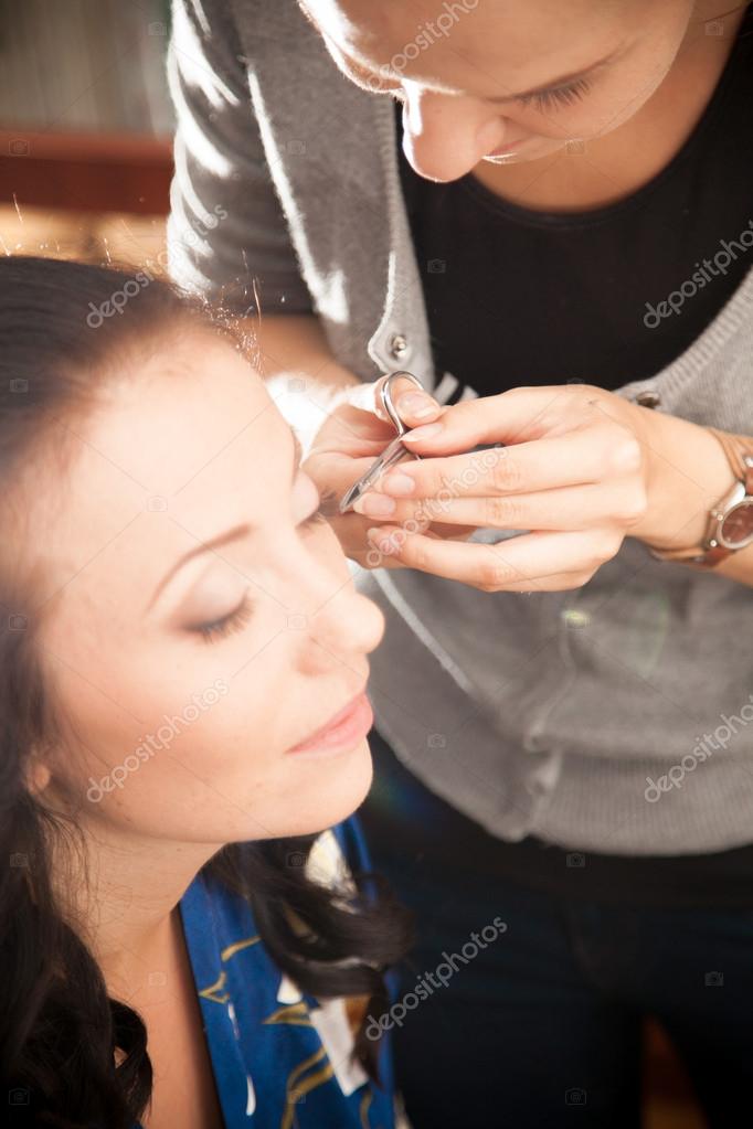 Portrait of makeup artist cutting eyelashes with scissors Stock Photo by ©Kryzhov 42117301