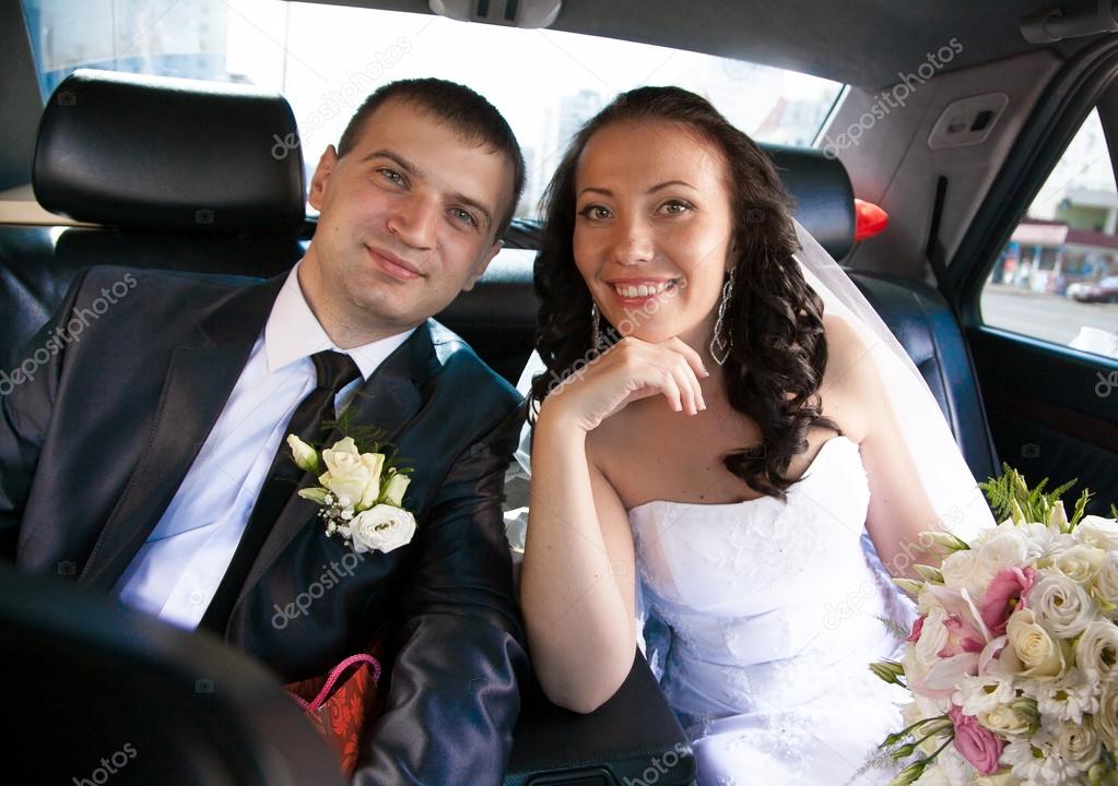 Married couple sitting on back seat of car and looking at camera