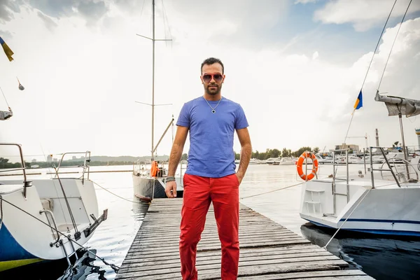 Stylish man posing on pier against sea and yachts — Stock Photo, Image