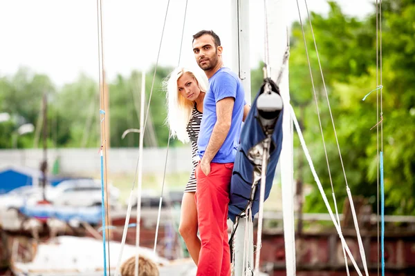 Pohledný muž a sexy dívka stojící na jachtě v přístavu — Stock fotografie