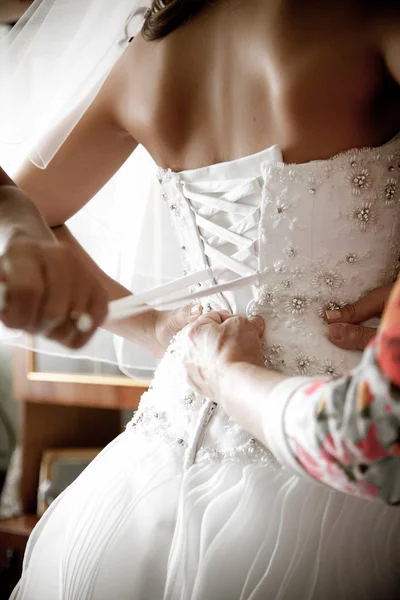 Tiro de dama de honra amarrando espartilho no vestido de noiva — Fotografia de Stock