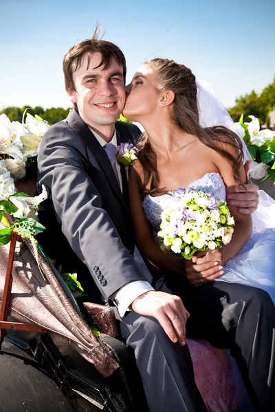 Retrato de noiva beijando noivo no treinador — Fotografia de Stock