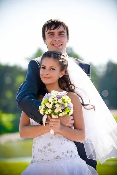 Groom embracing beautiful bride form back at park — Stock Photo, Image