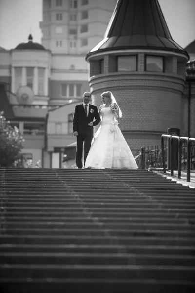 Bride and groom walking down the stairs at city — Stock Photo, Image