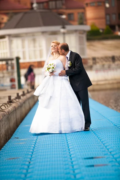 Retrato de novio besándose novia en muelle cerca del río — Foto de Stock