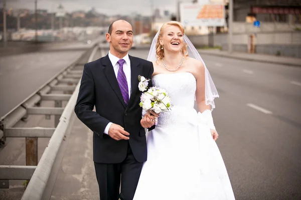 Volwassen bruid en bruidegom knuffelen op lege weg — Stockfoto
