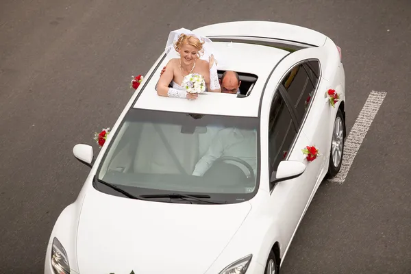 Blonde bride popping out of car sunroof — Stock Photo, Image