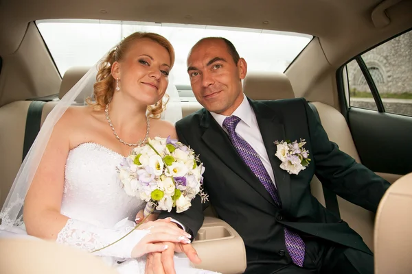 Bride and groom sitting on back seat of car — Stock Photo, Image