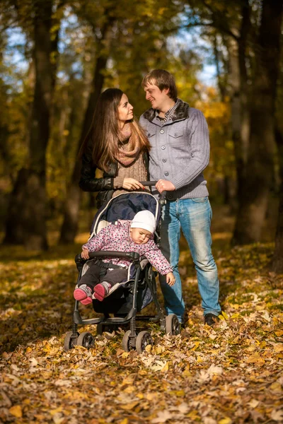 Couple walking with little daughter in buggy — Stock Photo, Image
