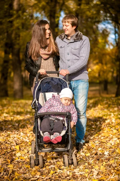 Family with little daughter in pram at autumn — Stock Photo, Image