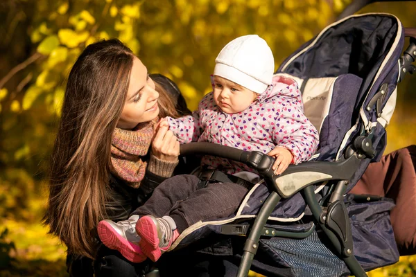 Молодая мама разговаривает с маленькой дочкой в коляске — стоковое фото