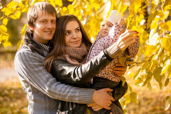 Familia divirtiéndose en el parque de otoño con su hija pequeña — Foto de Stock