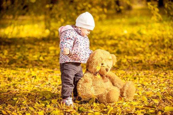 Girl playing with teddy bear at autumn park — Stock Photo, Image