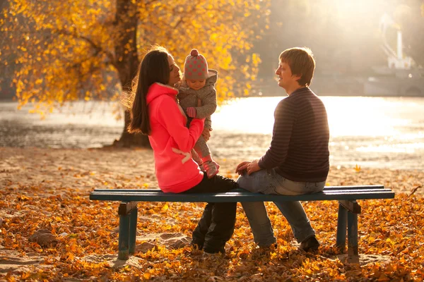 Famiglia si diverte al parco autunnale sulla panchina vicino al fiume — Foto Stock