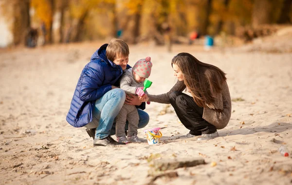 Семья играет на пляже с дочерью осенью — стоковое фото