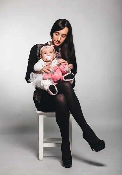 Frau sitzt auf Stuhl im Studio und hält Baby-Mädchen — Stockfoto