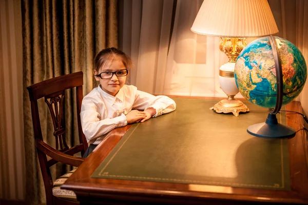 Menina em óculos sentada atrás da mesa no armário — Fotografia de Stock