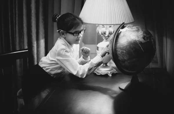 Girl doing homework and looking at globe — Stock Photo, Image