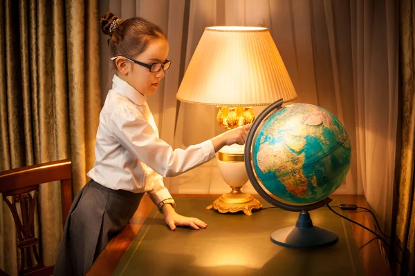 Joven colegiala estudiando globo en el escritorio — Foto de Stock