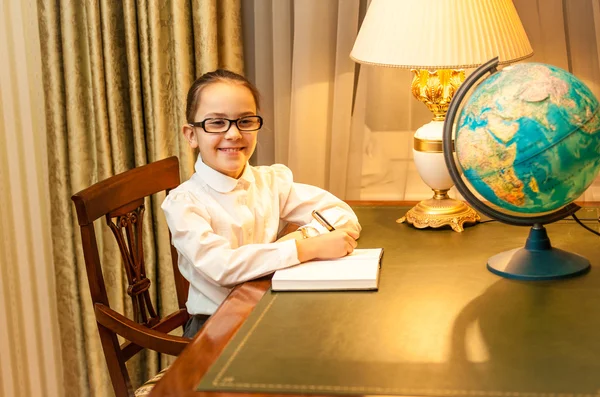 Sorrindo menina fazendo lição de casa na mesa clássica — Fotografia de Stock