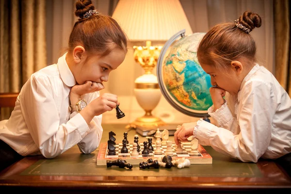 Sisters in school uniform playing chess — Stock Photo, Image