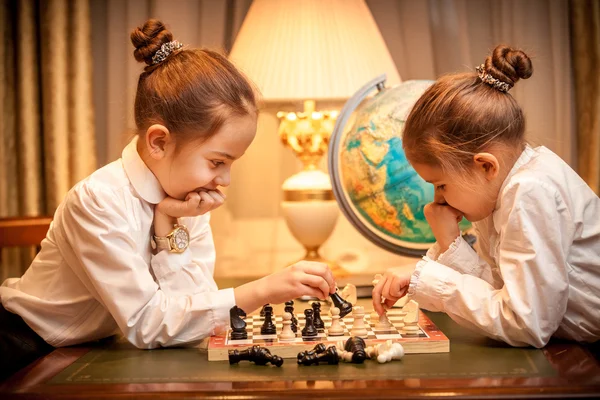 Girls in school uniform playing chess at cabinet — Stock Photo, Image