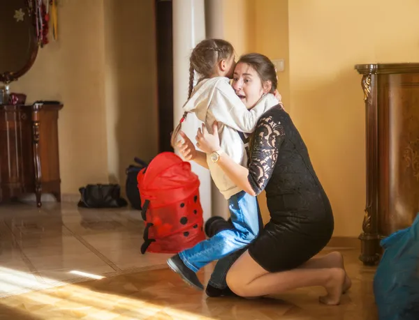 Ragazza che abbraccia sua madre dopo la scuola a casa — Foto Stock