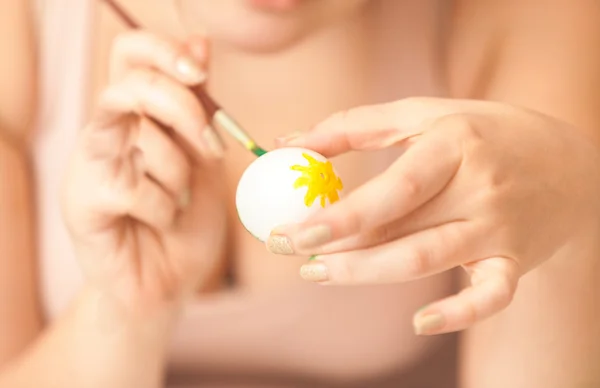 Kobieta trzyma białych jaj i malarstwo to z żółty — Zdjęcie stockowe