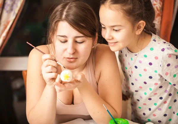 Portrait of mother showing daughter how to paint eggs — Stock Photo, Image
