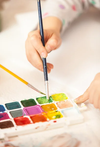 Girl holding brush and painting with watercolor — Stock Photo, Image
