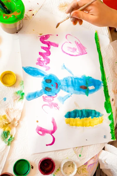 Shot of little girl drawing blue rabbit on canvas — Stock Photo, Image