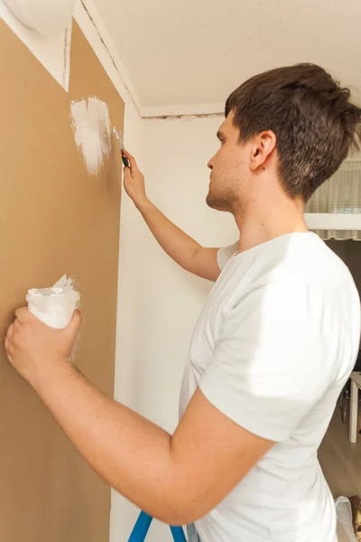 Retrato del joven alineando pared con masilla —  Fotos de Stock