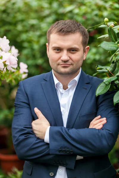 Portret van knappe bruidegom in pak poseren tegen boom — Stockfoto